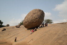 People By Huge Rock On Arid Landscape Against Sky