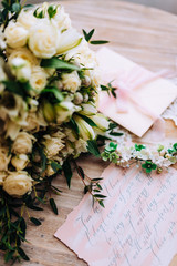 Wedding composition decorated with green white pearl floral jewelry and invitation letter on the wooden table. Jewelry closeup details from morning of the bride.