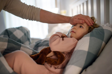 Wall Mural - Father checking forehead of small sick toddler daughter indoors at home.