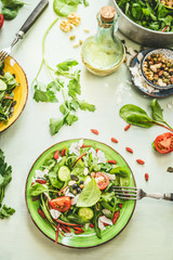 Healthy fresh green salad plate topped with various seeds and berries on light table background with olives oil and ingredients. Top view