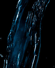 Wall Mural - A jet of blue water is isolated on a black .