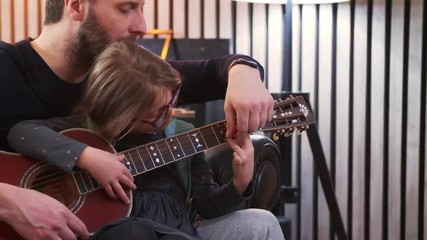 Wall Mural - Dad and daughter plays guitar together.Little girl learning guitar with her father at home.Front view.Guitar class at home