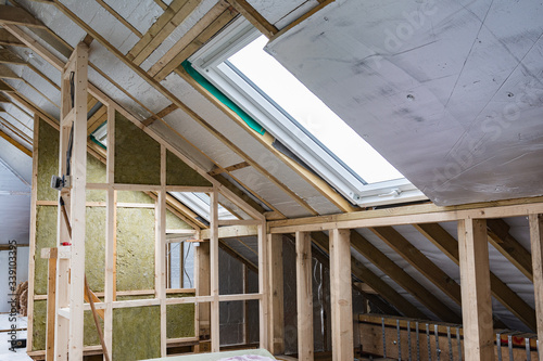 Loft conversion, unfinished project, silver insulation, roof windows, wood structure of the walls, selective focus
