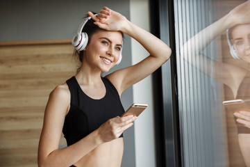 Canvas Print - Photo of smiling seductive woman using headphones and smartphone