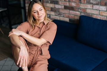 Woman sitting in chair in dark living room, looking at away. Concept of home coziness .