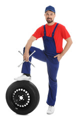 Canvas Print - Full length portrait of professional auto mechanic with lug wrench and wheel on white background