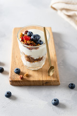 Wall Mural - Parfait. Glass with homemade granola with yogurt and fresh berries on white concrete background. Dieting, recipe