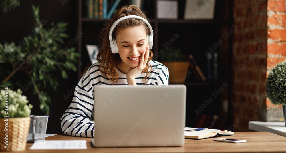 Excited woman in headphones having conversation on video chat while using laptop at home. - obrazy, fototapety, plakaty 