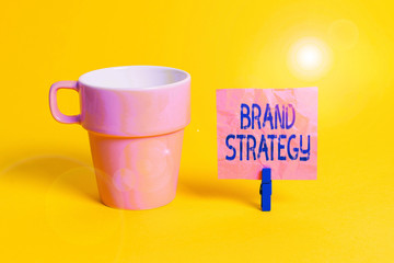 Fototapete - Text sign showing Brand Strategy. Business photo showcasing Longterm plan for the development of a successful brand Cup empty paper blue clothespin rectangle shaped reminder yellow office