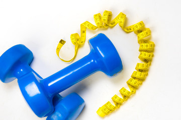 dumbbell and centimeter on a light background