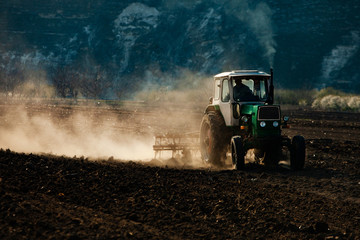 Farmer in tractor preparing land. Agricultural works at farmlands. agricultural work plowing land on a  tractor. Tractor on a farmer field in Moldova, Europe.