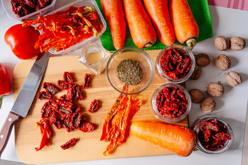 Sun-dried tomatoes and dried carrots with olive oil and Provencal herbs. The process of making dried tomatoes. Ingredients for Vegetable Chips top view