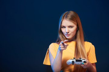 Wall Mural - Alluring girl holding video game joystick pointing finger at you