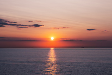 Wall Mural - Sunset in the ocean with soft waves and red cloudy sky. Sea sunrise background. Landscape photography