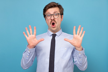 Wall Mural - Portrait of happy smiling man showing ten fingers, isolated over blue background