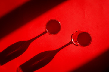 Two glasses with red wine on red background in natural sunlight with shadows