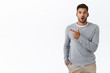 © Cookie Studio - Impressed handsome guy have no words, standing speechless and amused pointing left, check-out interesting logo or promo offer, folding lips say wow, gasping astonished, stand white background