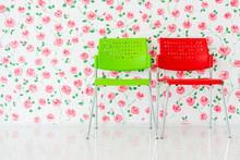 Green And Red Plastic Chairs In The Room, Wall Against Red Flower Background