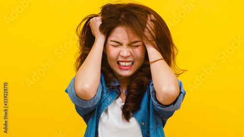 Fotomural Portrait of young Asian lady with negative expression, excited screaming, crying emotional angry in casual clothing and looking at the camera over yellow background