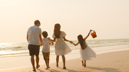 Asian young happy family enjoy vacation on beach in evening. Dad, mom and kid relax walking together near sea when sunset while travel holiday trip. Lifestyle travel holiday vacation summer concept.