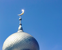 Mosque Of Muslim. Crescent On Copper Covered Dome And Minaret Of Mosque Against Blue Sky. Symbol Of Islam And Ramadan.