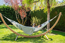 Young Relaxed Girl Reading Travel Book In Hammock In Garden At Home At Bright Sunny Day. Slow Living, Gadget Detox And Weekend Leisure Activity. Quarantine And Self Isolation Period