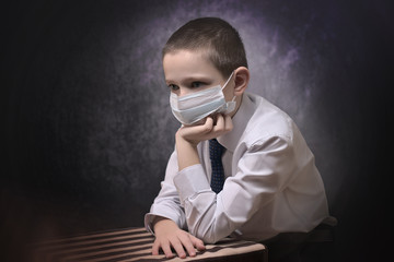 A boy in a medical mask sits at home sad and lonely. Quarantine, epidemic corona virus.