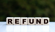 The concept of the word REFUND on cubes on a beautiful green background