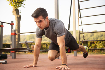 Sportive young man doing exercise with trx gym equipment outdoor