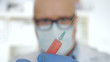 © EuStock - Doctor Wearing Protecting Gloves and Face Mask Keeping in His Hand an Injection with a Vaccine, Antidote, and Treatment for Covid-19 Virus Pandemic