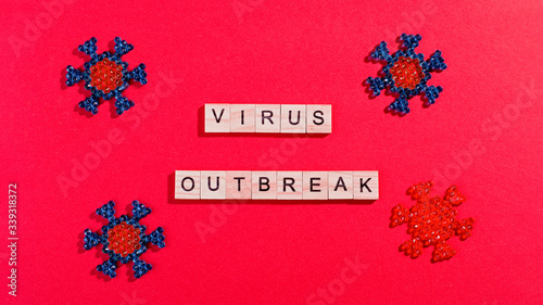 Words corona virus outbreak made of wooden blocks with coronavirus model on red background, flat lay, top view. Pandemic concept