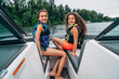 © Inti St. Clair - Smiling happy girls on boat on lake surrounded by trees, wind blowing hair