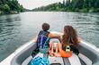 © Inti St. Clair - Girls in life jackets sitting on bow of boat on lake surrounded by trees