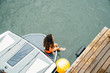 © Inti St. Clair - Girl in life jacket sitting on boat next to dock on lake with feet in water