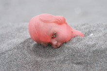 Close-up Of Abandoned Doll In Sand At Beach
