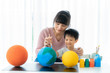 © ake1150 - Asian preschool student boy with mother painting the moon learning about the solar system at home, Homeschooling and distance learning..