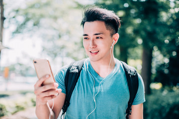 happy young man  walking on street and using mobile phone