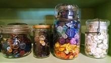 Close-up Of Buttons In Jars On Rack