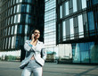 © Raisa Kanareva - young business woman uses a mobile phone in front of a modern business center