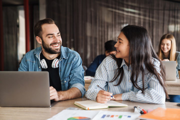 Sticker - Photo of joyful students using laptop and writing in exercise book