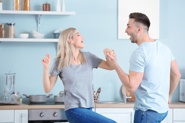 Wall Mural - Happy dancing young couple in kitchen