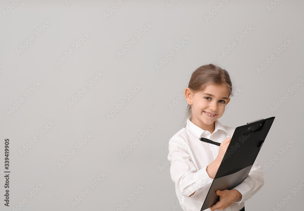 Little businesswoman with clipboard on grey background