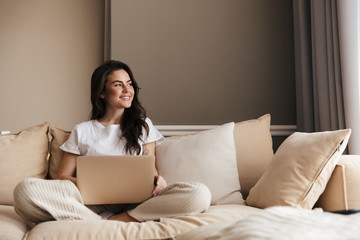 Wall Mural - Beautiful young brunette woman relaxing on a couch at home