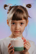 Liitle girl with cup of warm sweet drink on a colorful background.