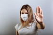 © lightscience - Female lady in face mask showing stop sign with her hand to prevent spreading of the viruses. Selective focus