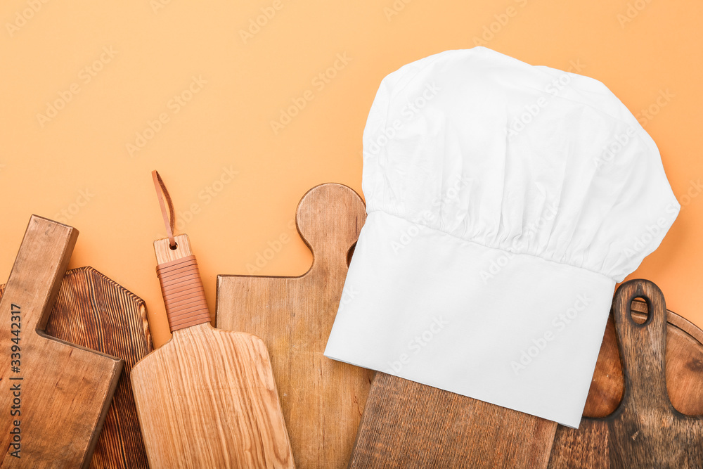 Composition with chef's hat and wooden boards on color background