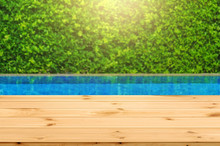 Wooden Table In Front With Empty Space For Advertise Display And Blurred Background Of Swimming Pool And Green Garden