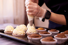 Chocolate Cupcakes With A Swirl Of Cream.Female Hands Fill Cupcakes On A Baking Sheet.