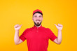© Evrymmnt - Young handsome delivery guy wearing red uniform and cap holding posing over isolated yellow background. Portrait of friendly bearded man in polo shirt and baseball hat. Copy space for text.