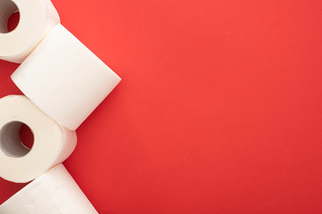 Wall Mural - top view of white toilet paper rolls on red background with copy space